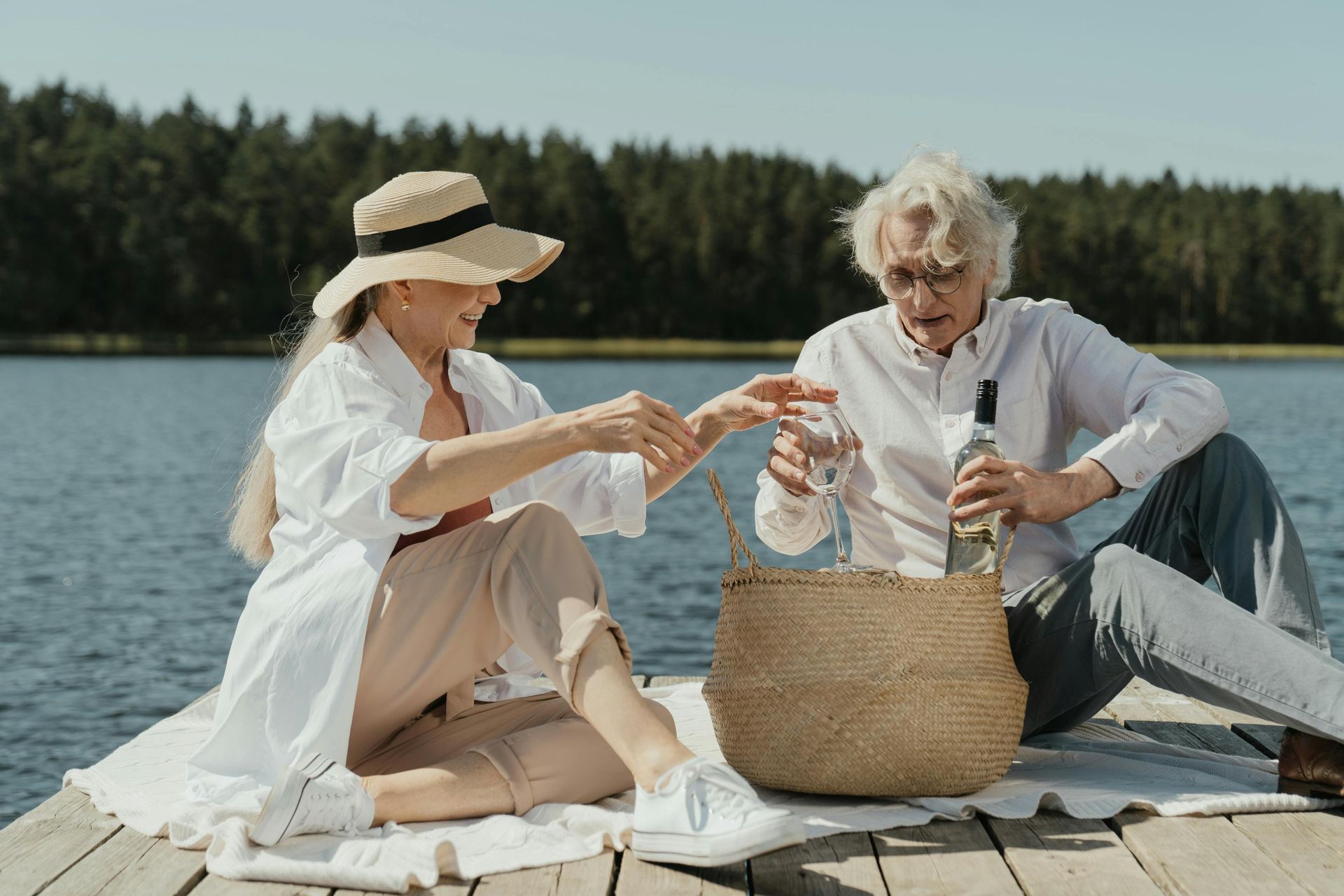 Ein junges Rentnerpaar macht ein Picknick auf einem Steg an einem See